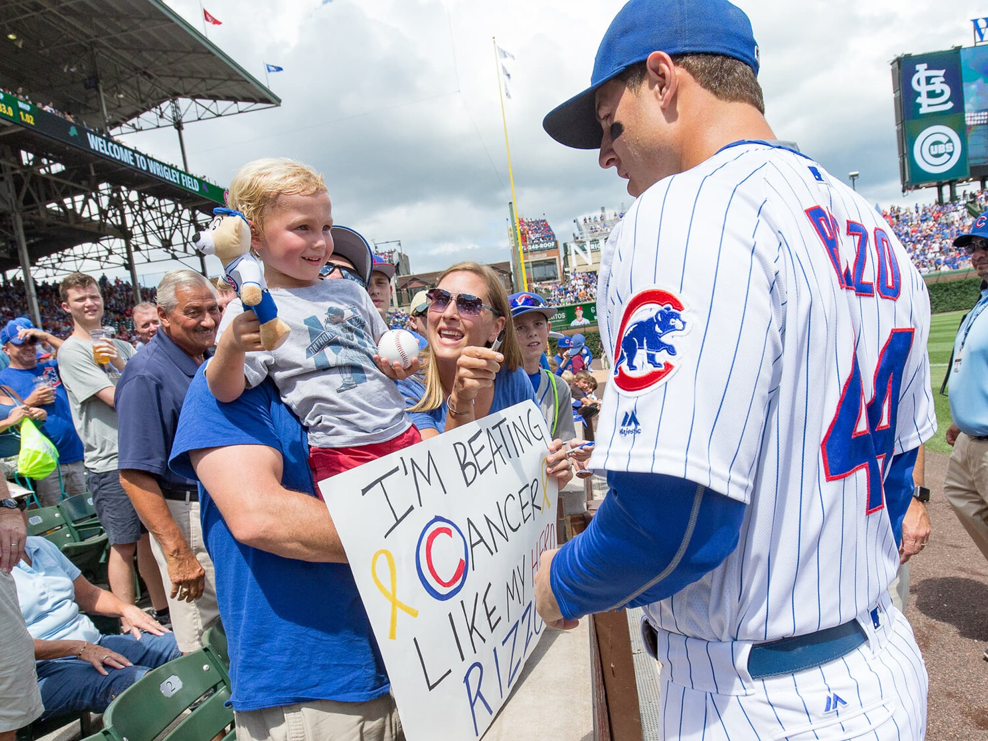 Chicago Cubs player Anthony Rizzo meets a young fan holding a sign about beating cancer at Wrigley Field