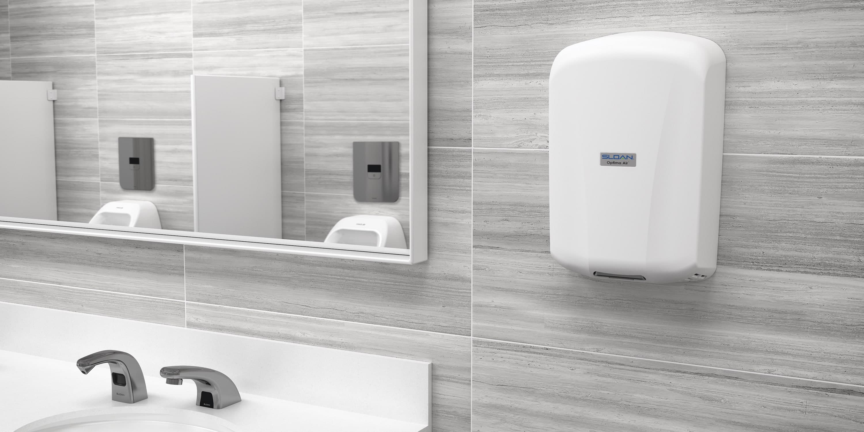Modern restroom sink area with mirrors, soap dispensers, and a wall-mounted paper towel dispenser on gray tile walls.