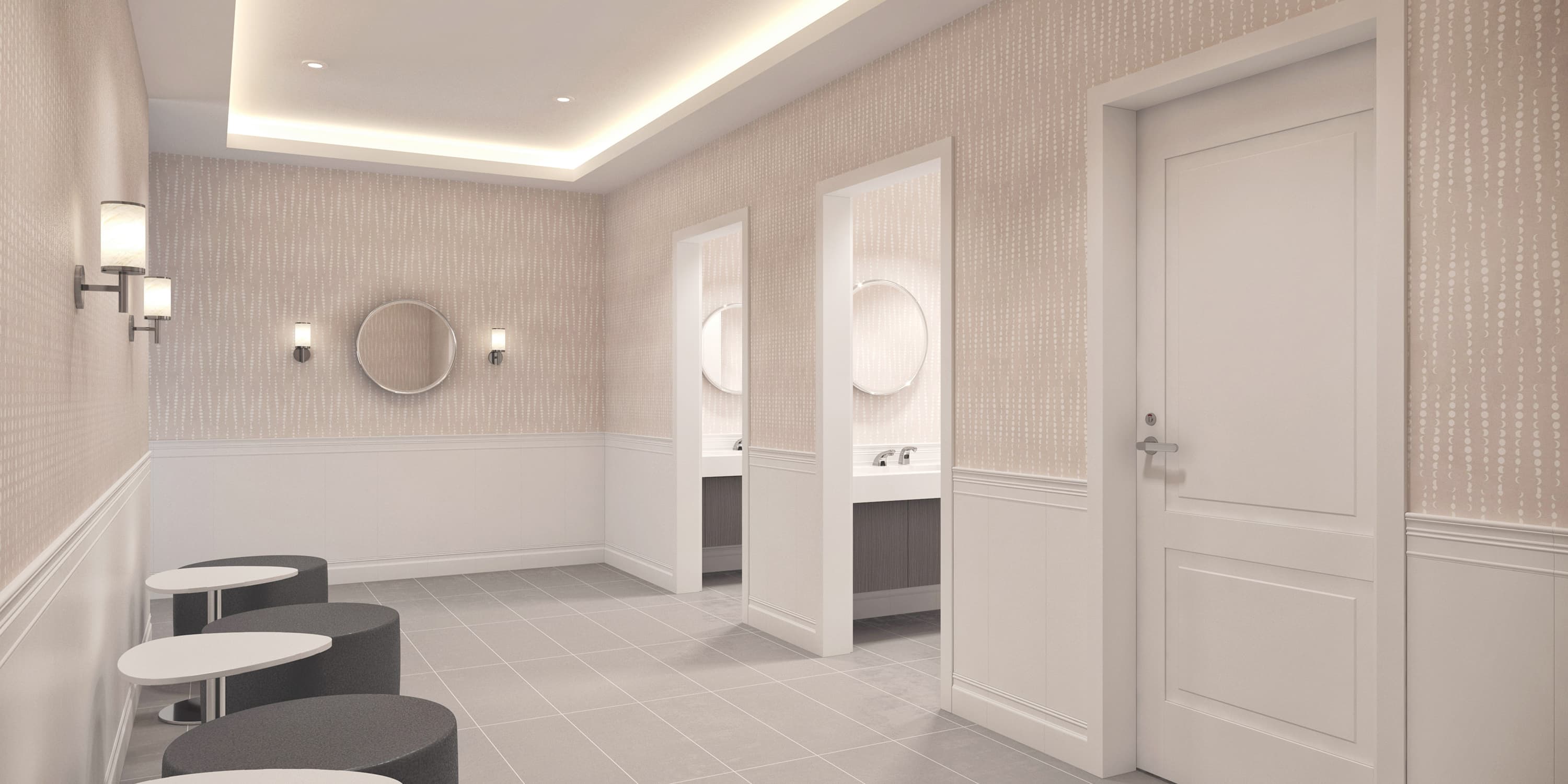 Modern restroom with patterned wallpaper, round mirrors, and stall entrances, designed with soft lighting and gray tile flooring.