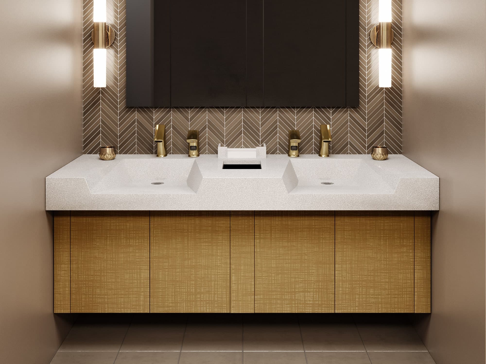 Elegant commercial restroom vanity with a white countertop, integrated sinks, and polished brass touchless faucets, accented by wall sconces and a decorative tile backsplash.