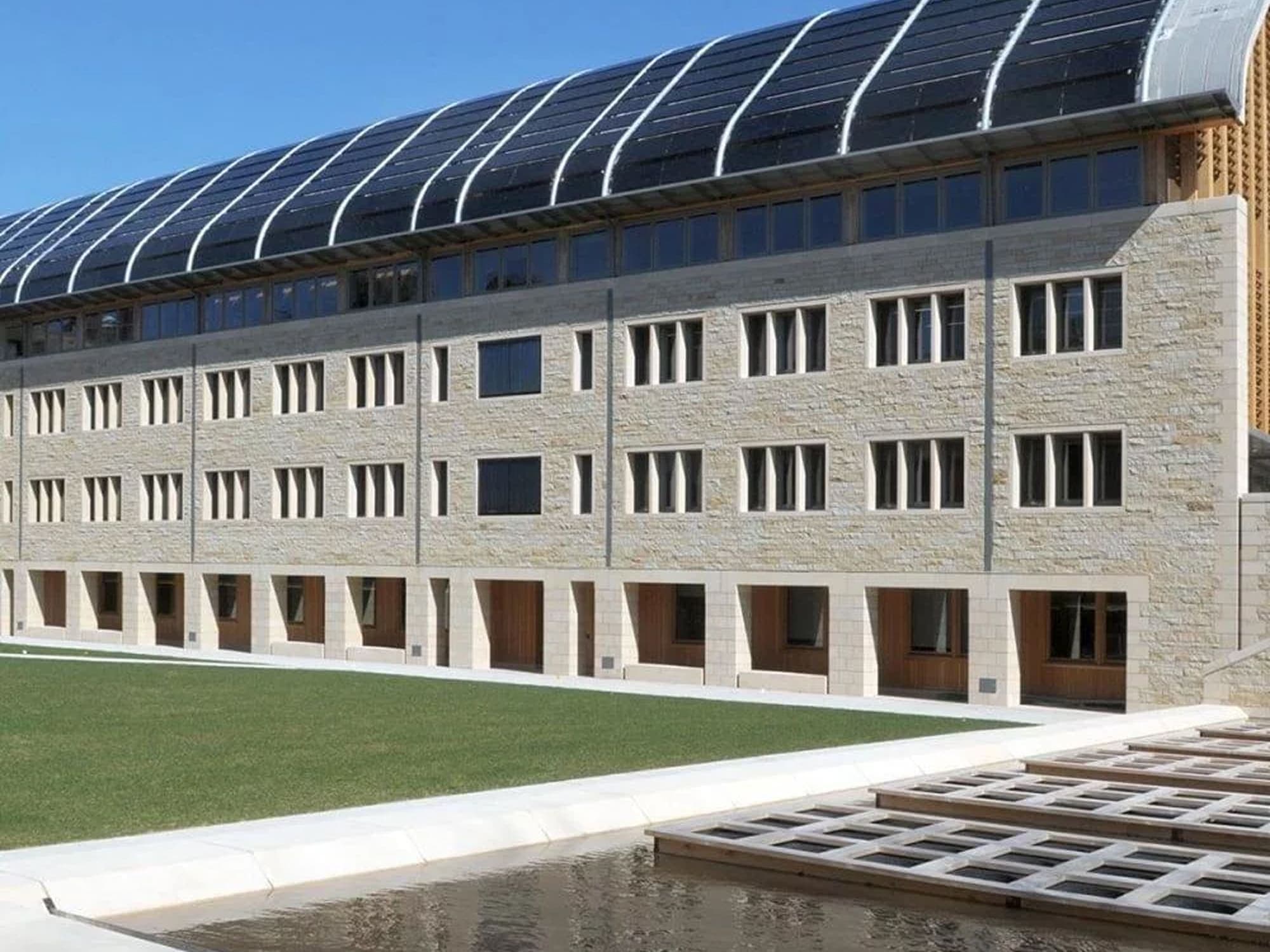 Modern education building with large windows and a curved rooftop structure.