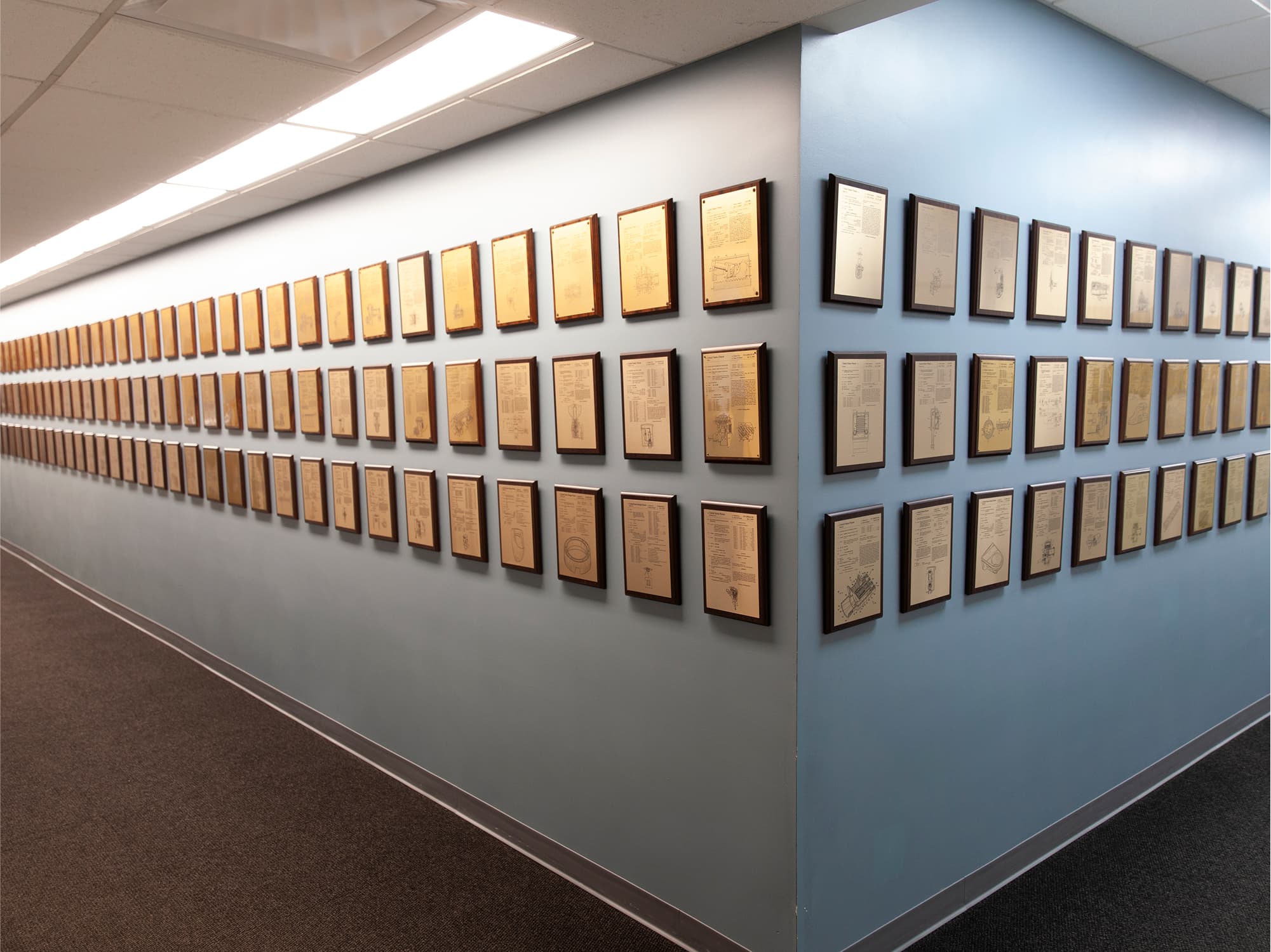 Patent plaques in a row along a hallway in Sloan's HQ