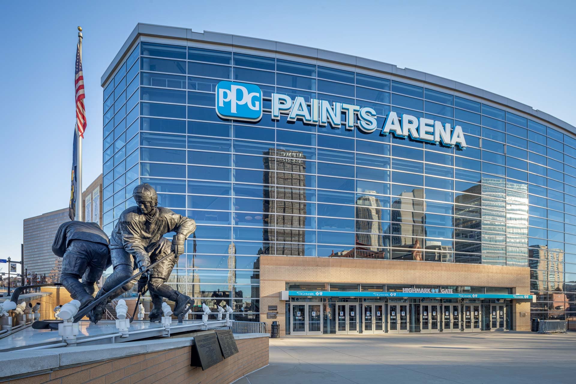 street view of glass exterior arena building with statue infront of it