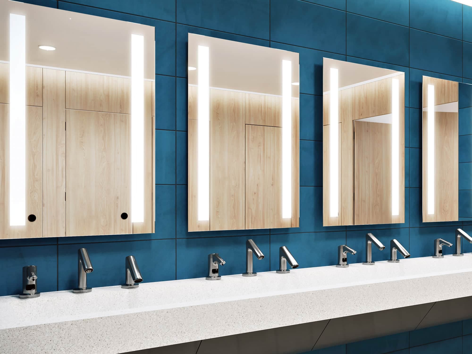 Modern restroom with blue tiled walls, long white countertop sinks, and mirrors with vertical lights.