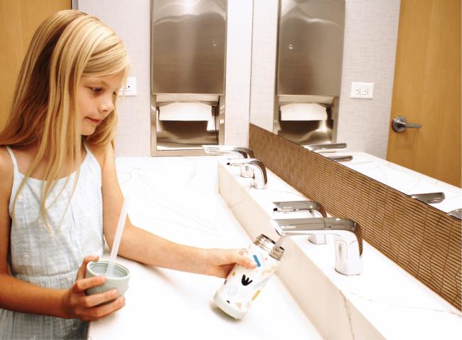 Girl filling up water canister using Sloan faucet