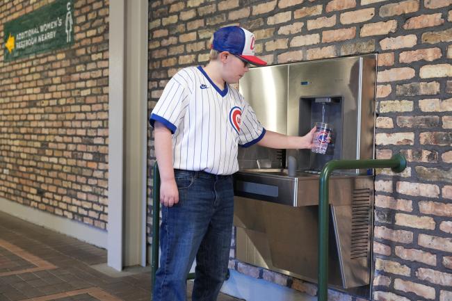 A young Cubs fan filling up his water cup at the DRS120 DropSpot On-wall Bottle Filler with Bi-level Cooler at The Friendly Confines