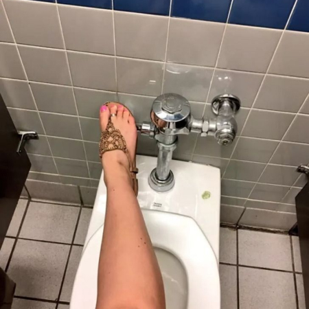 Person using their foot to flush a toilet